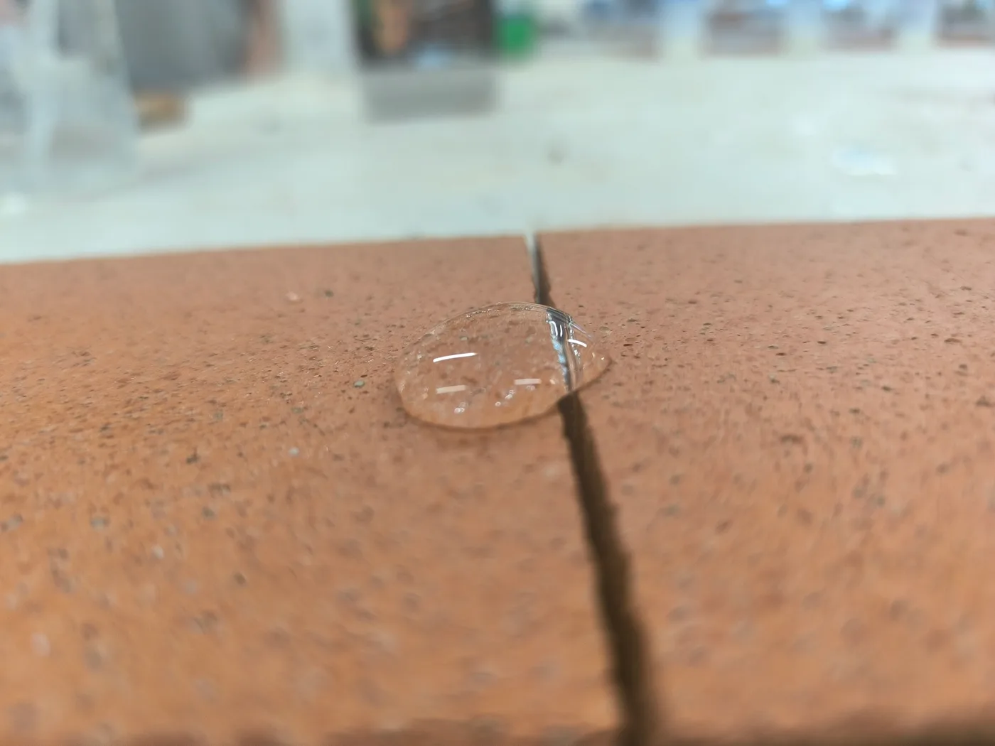 Goutte d'eau qui perle sur dalle en terre cuite traitée au SCUDO, joint de 2 à 3 mm visible