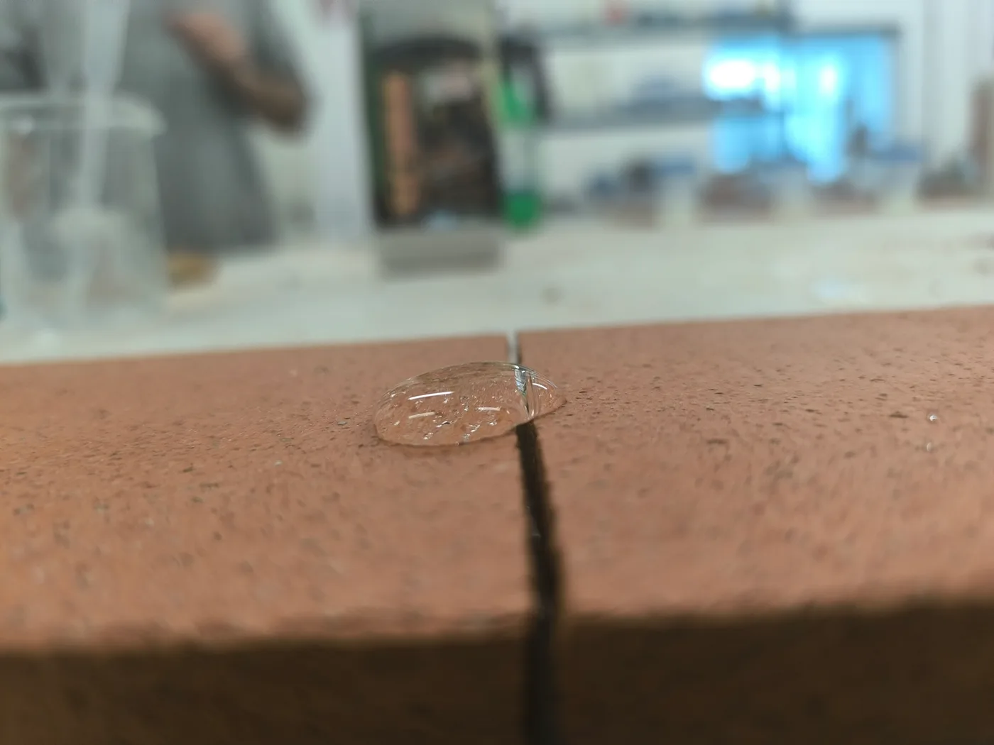 Effet nanotechnologique SCUDO : goutte d'eau au-dessus d'un joint entre deux dalles en terre cuite